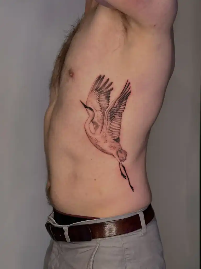 Delicate fine line bird tattoo on the ribs.
