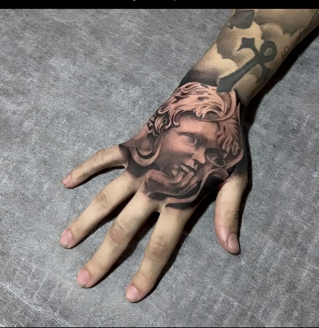 Cherub statue hand tattoo by Paulo Rodrigues at XOXO Tattoo Dublin